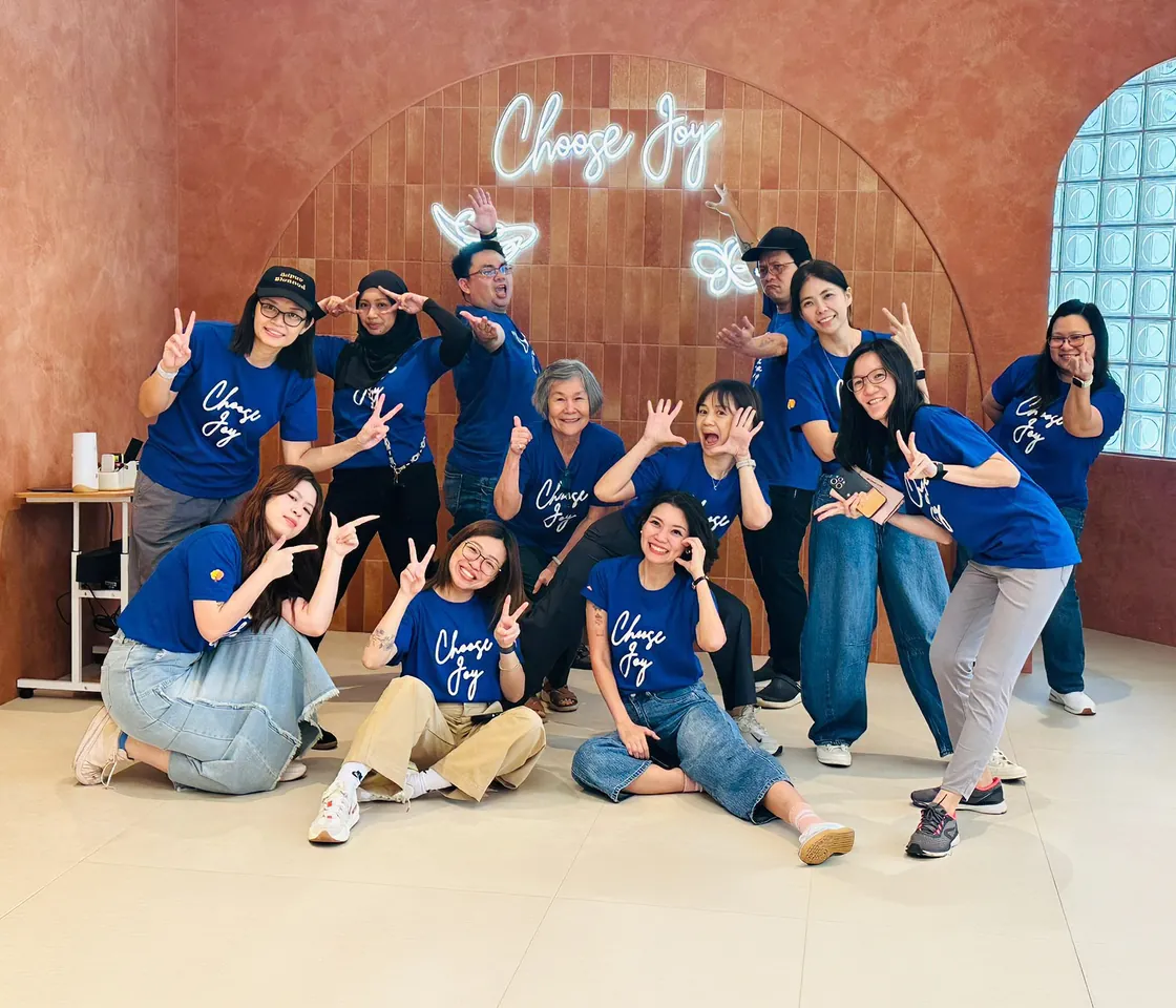 CHCSA staff gathered for a team photo beneath a Choose Joy sign at the office.